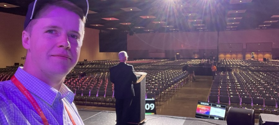 Peter on stage in a large hall, a speaker at the podium behind him